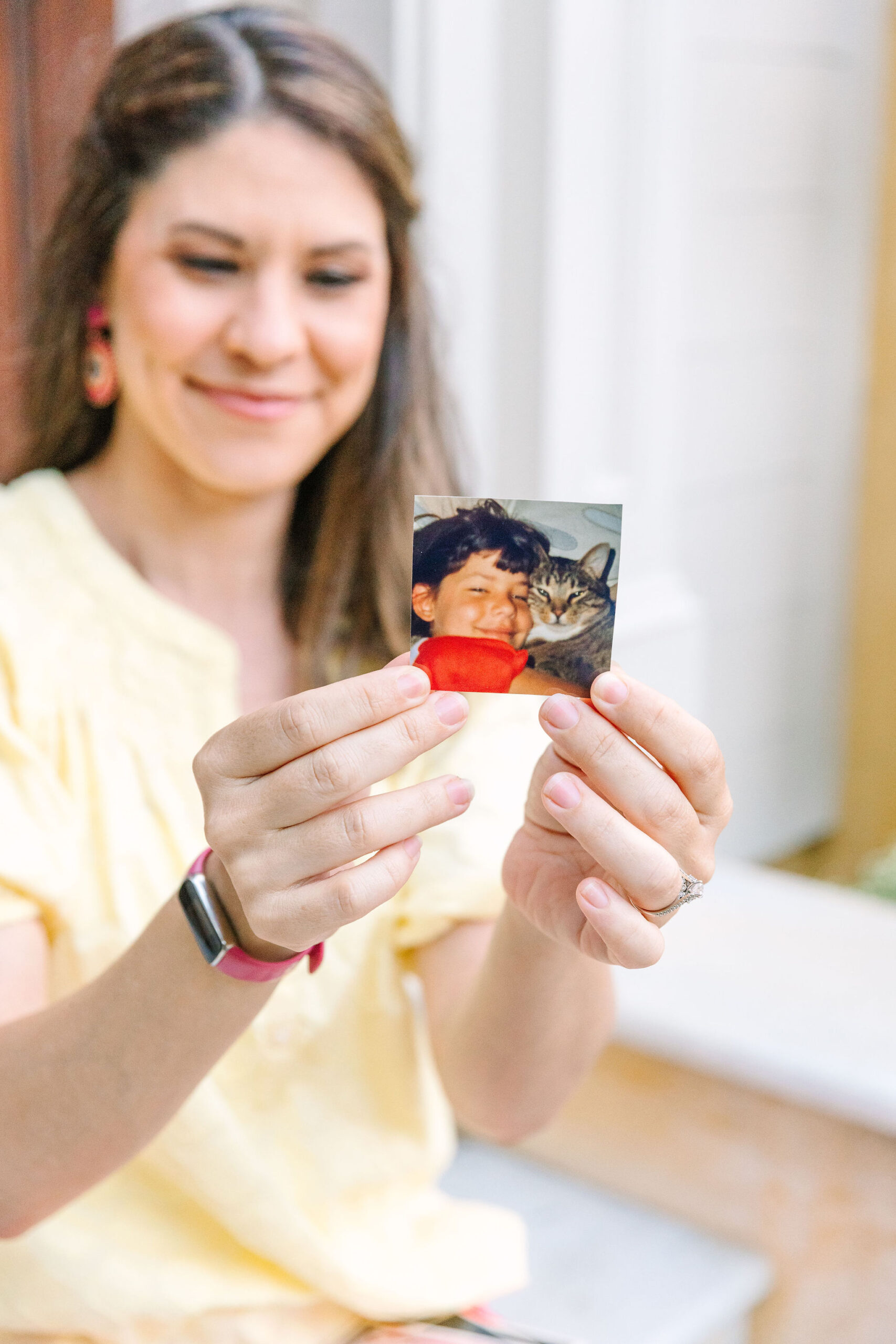 photo of Tara Lynn holding up a childhood photo of herself with her cat